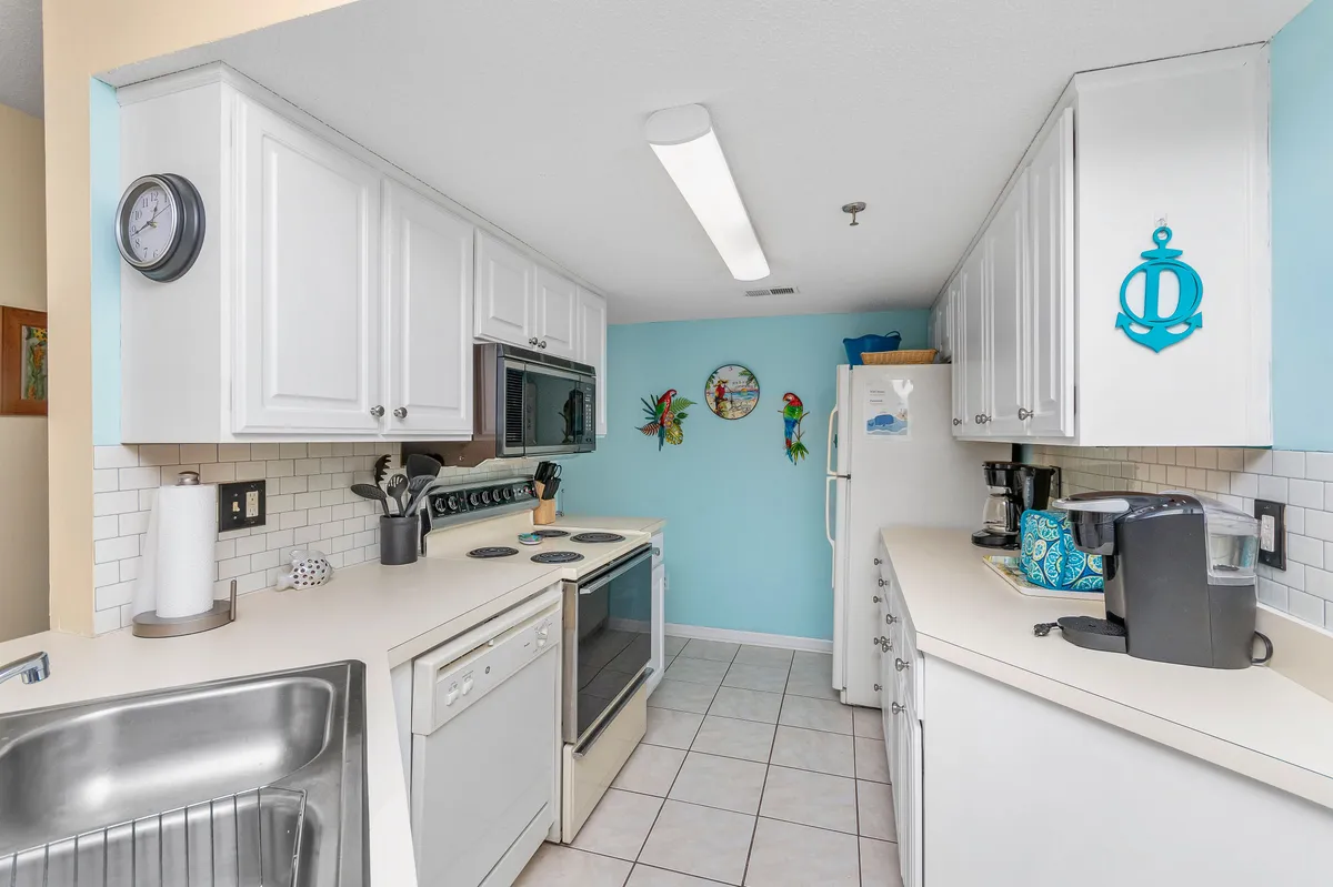 A fully stocked kitchen with white cabinetry, light blue walls, and modern appliances. The space is accented by decorative wall art and is designed for cooking, baking, and gathering, encouraging guests to enjoy preparing meals together.
